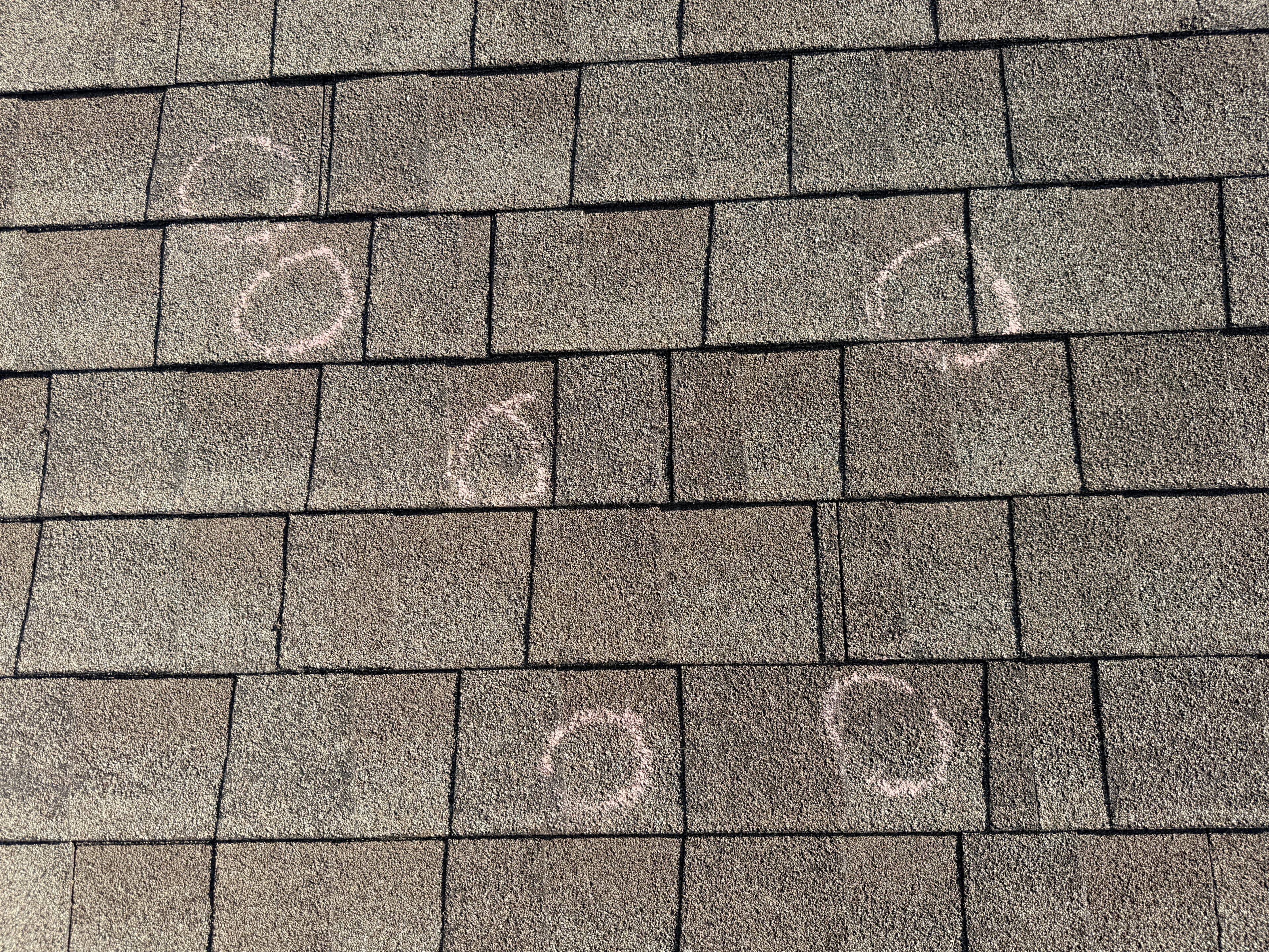 five spots of hail damage marked on roof shingles