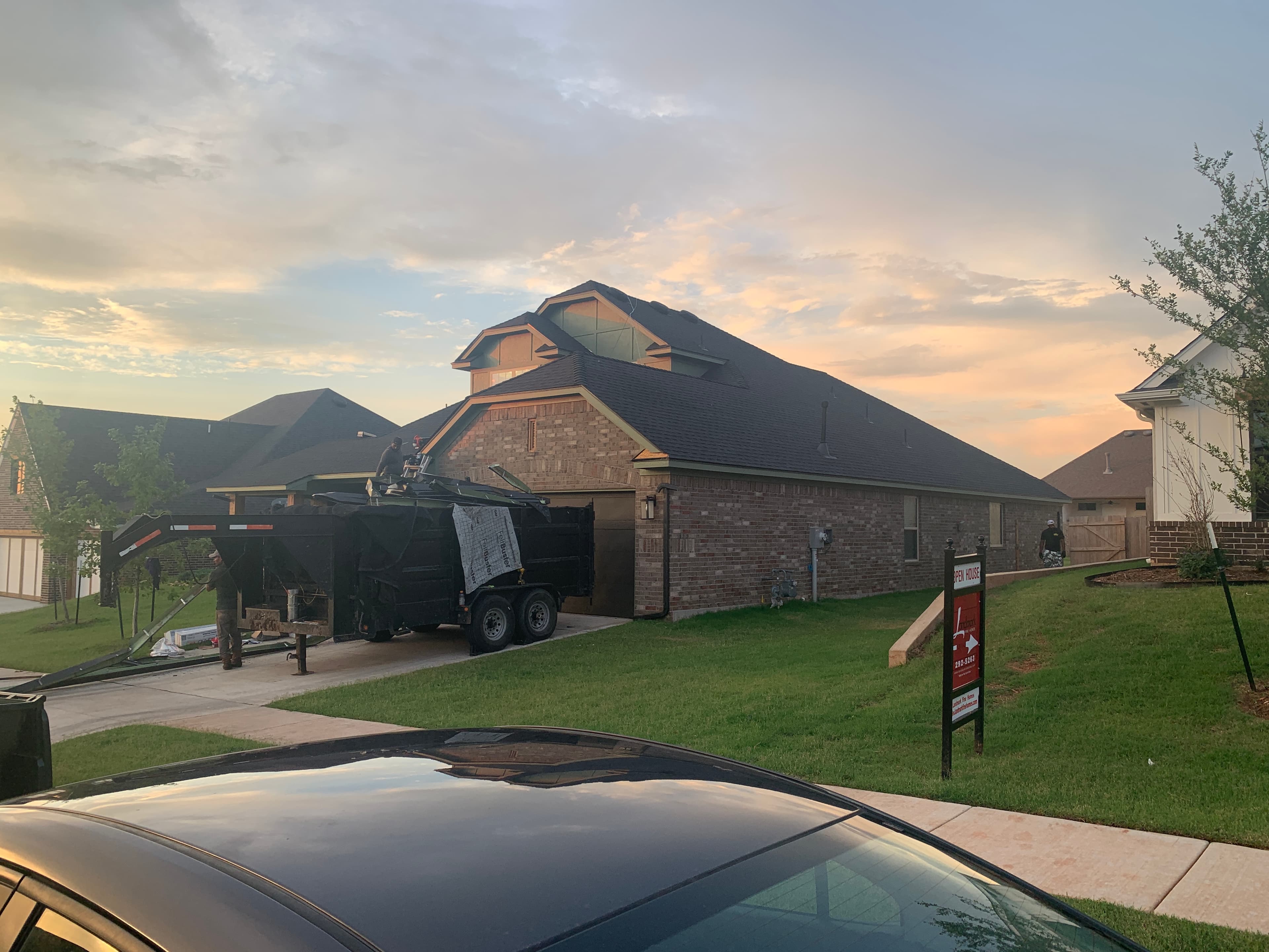 Debris trailer parked in driveway during a residential roof tear-off and replacement in Norman, OK.