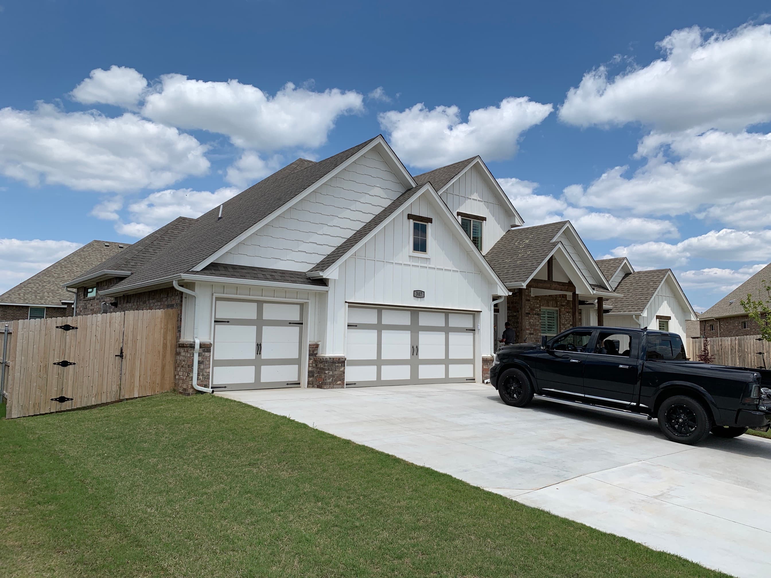 Front elevation of a white board-and-batten modern farmhouse in Oklahoma City with a new multi-gable architectural shingle roof.