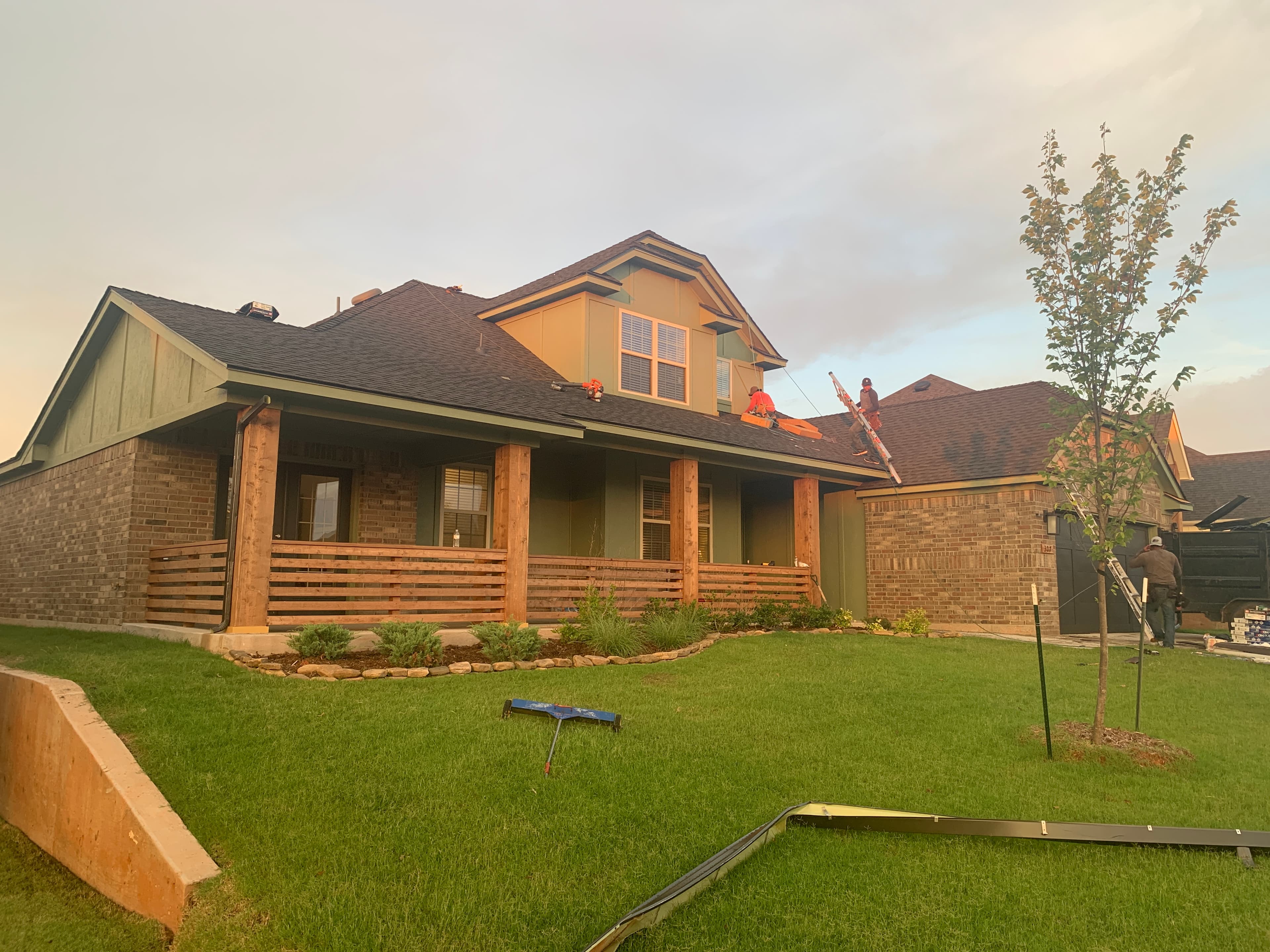 Professional roofing crew installing architectural shingles on a Craftsman-style brick home in Norman, OK.