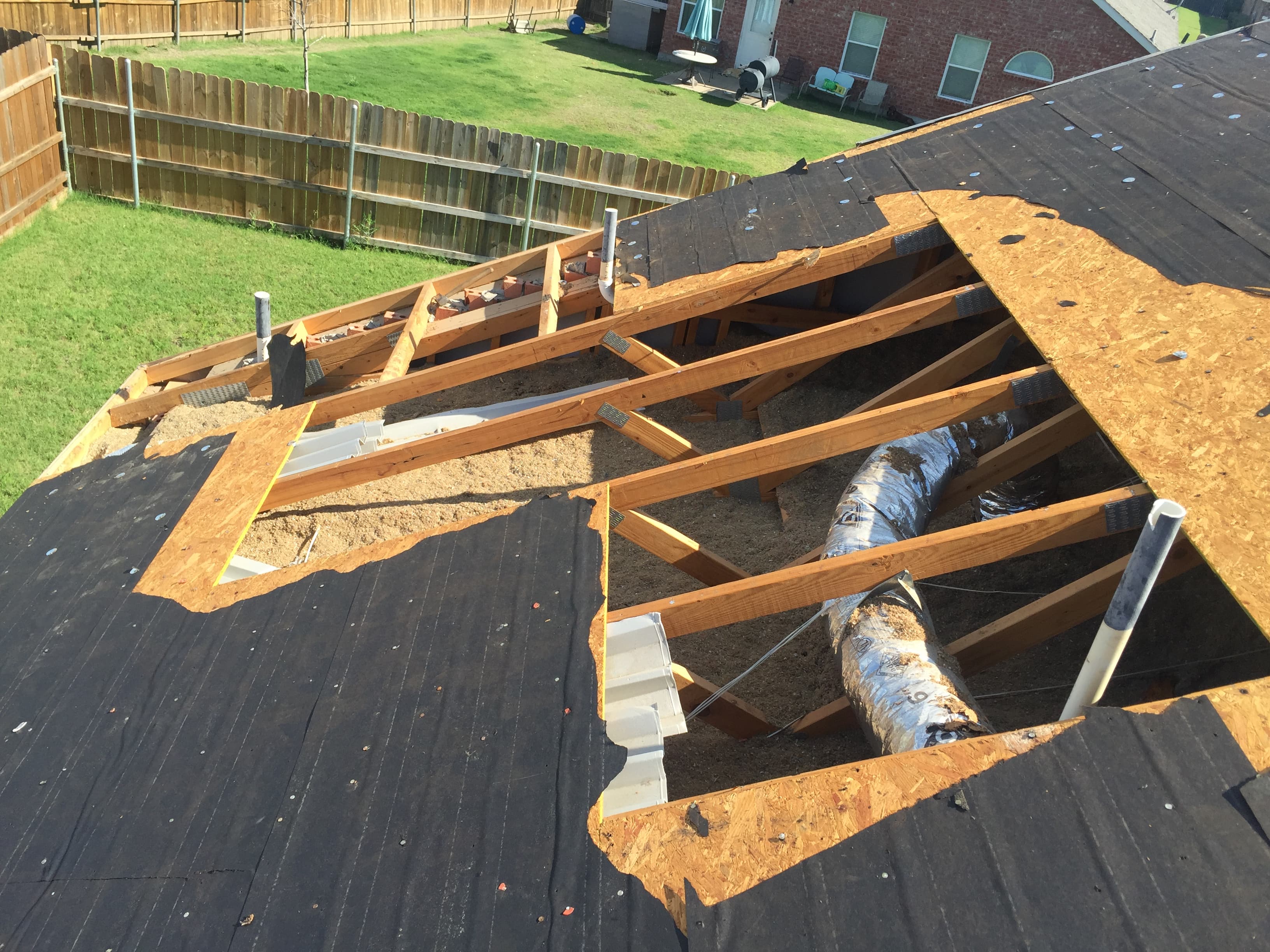 Roofing contractor tearing off old damaged shingles to inspect and prep the wooden roof deck during a residential replacement project.