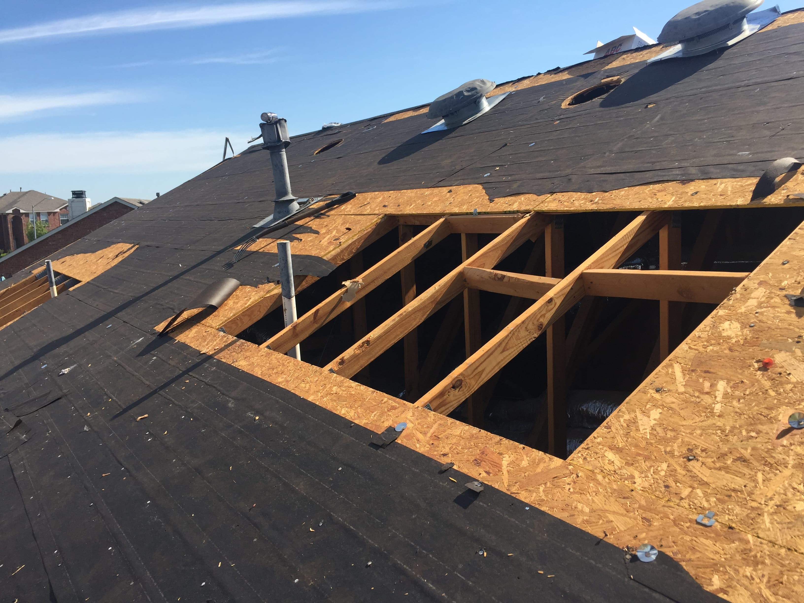 Work-in-progress residential roof replacement showing protective synthetic underlayment and ice and water shield installed over the bare decking.