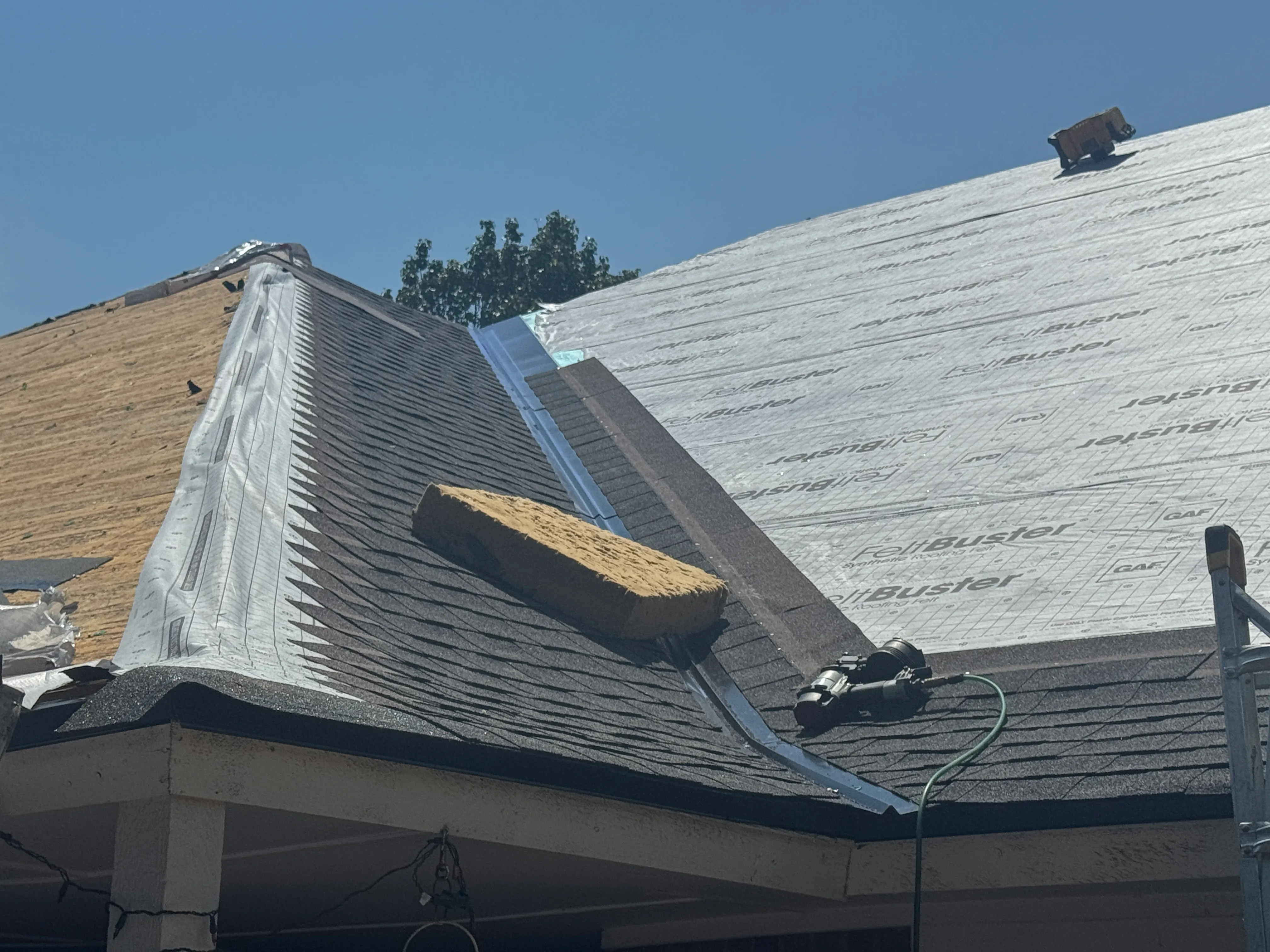 residential roof undergoing replacement, featuring a section of exposed wooden decking in progress OKC