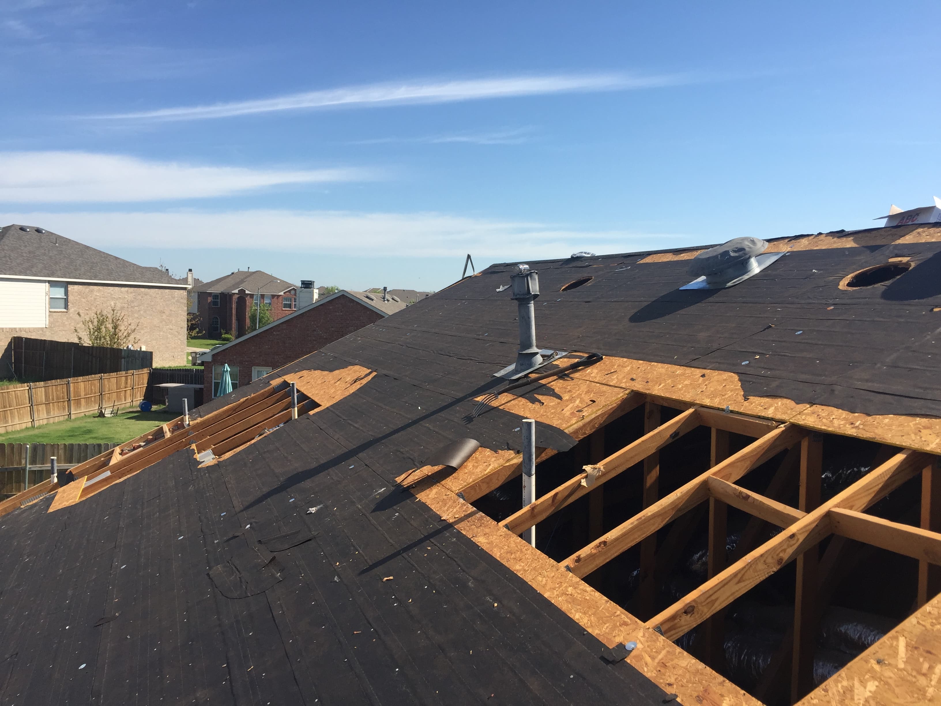 Professional roofers actively installing new dark architectural shingles on a steep-slope residential roof replacement.