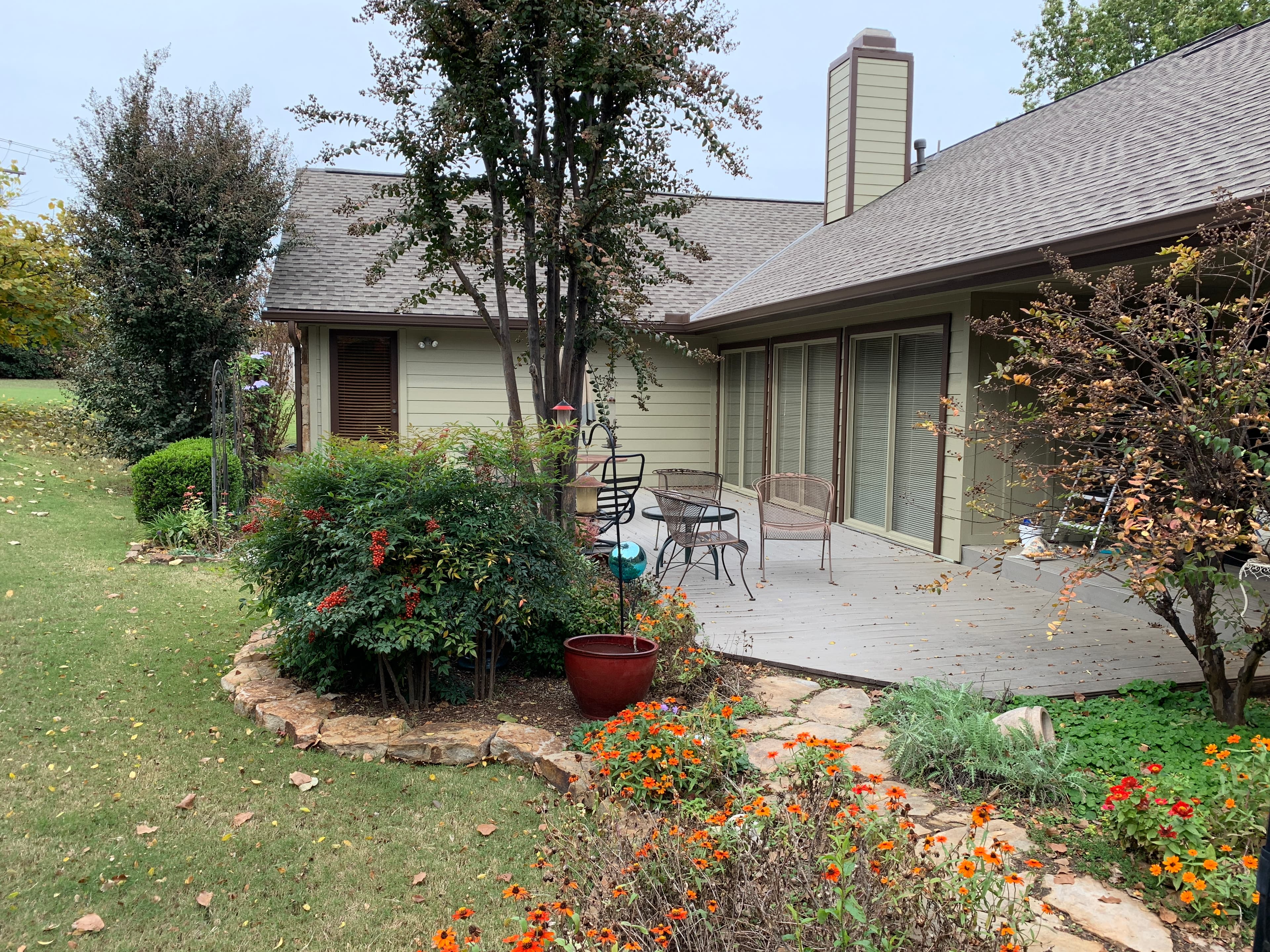Close backyard patio view showing new architectural roof shingles installed above a stone pathway and timber deck in Edmond, OK.
