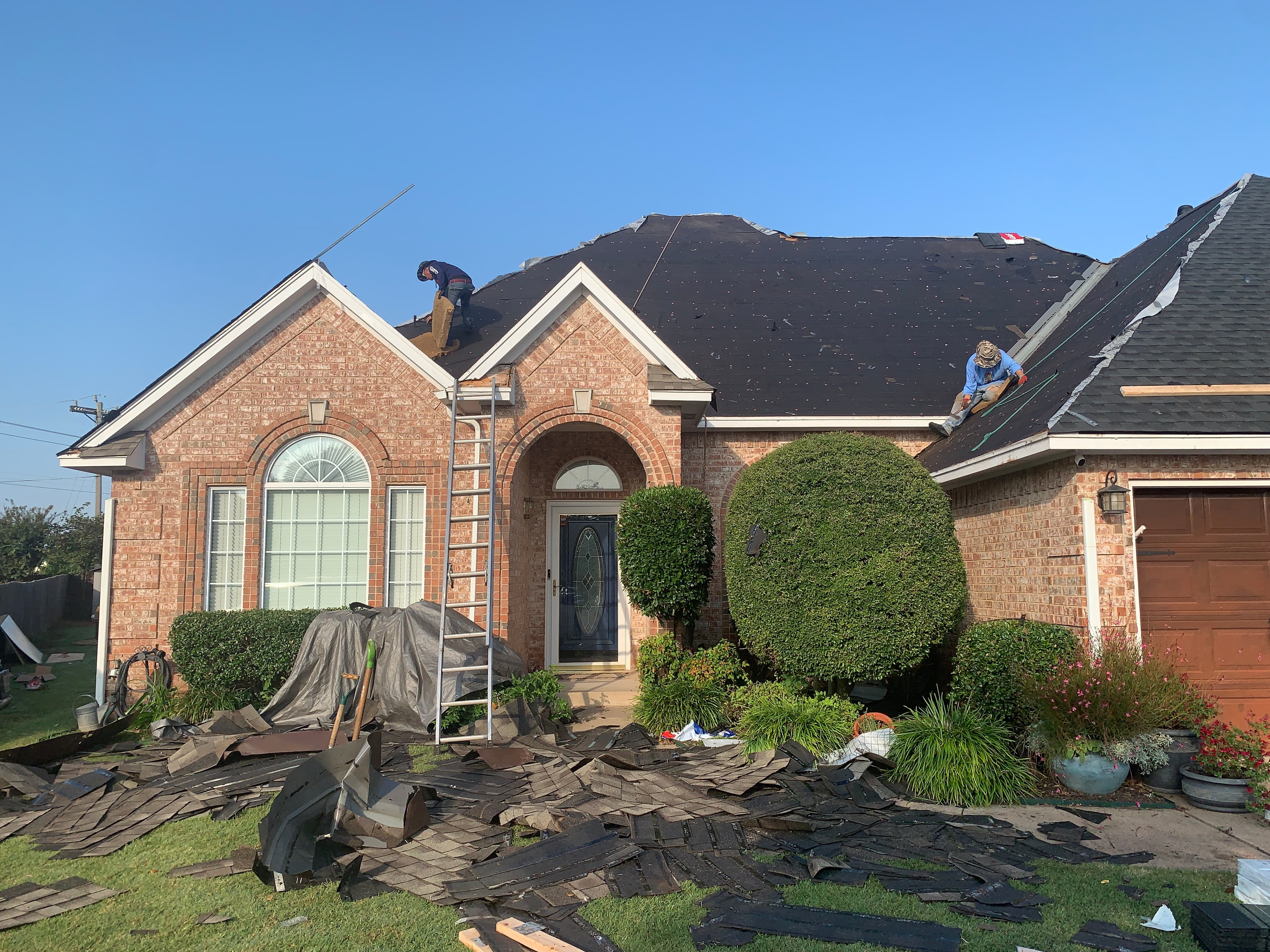 Complete roof tear-off in progress on an Oklahoma City brick home with synthetic underlayment installation underway.